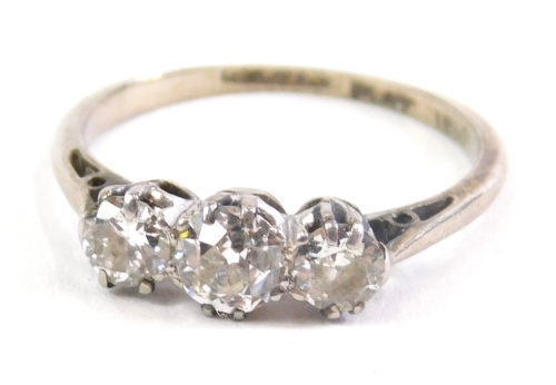 A three stone diamond ring, on part pierced shank, illusion set, marked PLAT, size J, 1.9g all in.