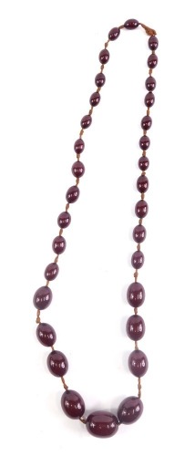 A faux amber necklace, set with graduated cherry coloured beads on a plain string, 70cm long.