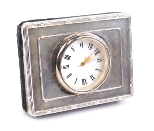 An Elizabeth II silver watch case, with velvet easel back inset with a watch with Roman numeric dial, London 1996, 7cm wide and a small silver coloured evening purse.