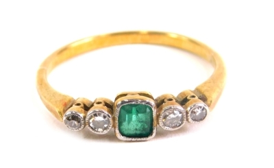 An Art Deco style dress ring, baguette cut with central emerald flanked by two small diamonds on an unmarked shank, size M.