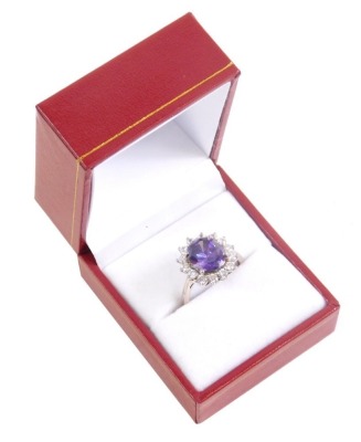 A dress ring, claw set with central purple stone, with floral surround of small diamonds on a part pierced shank, size M.