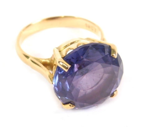 A dress ring, claw set with large amethyst coloured stone, the part pierced shank marked 18ct, size N.