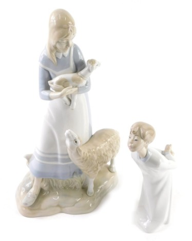 A Lladro figure of a child, with arms behind back, printed marks beneath, 20cm high, and a similar figure of a girl holding lamb (2, AF)