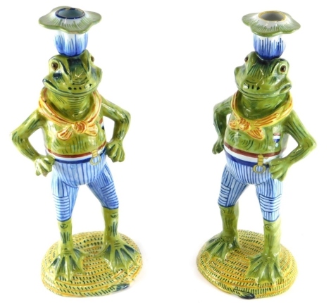 A pair of Continental tin glazed earthenware frog candlesticks, each vibrantly decorated predominantly in blue, green and yellow, marked beneath, 31cm high. (2)