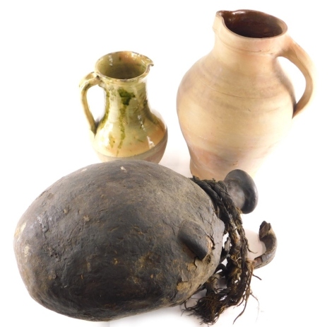 A West Country style lead glazed stoneware jug, with beak spout, partially glazed in green and marked, 28cm high, a further undecorated stoneware ewer, and a large globular flask. (3)