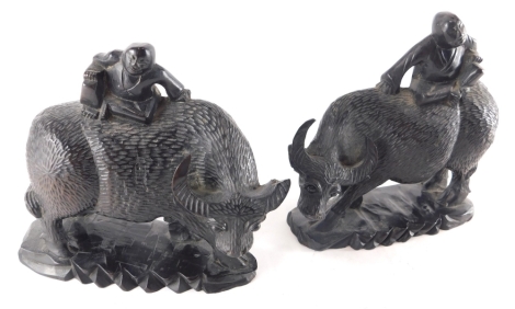 A pair of heavily carved and ebonised Chinese figures on children on buffalo, each on shaped bases, 18cm high.