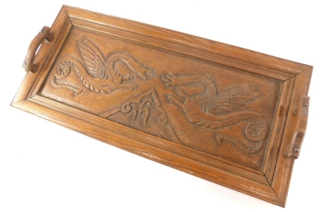 An early 20thC oak tray, of rectangular form with shaped handles heavily carved with dragons, 57cm wide.