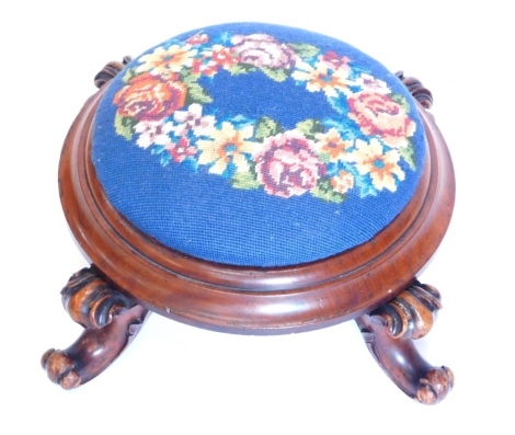 A Victorian mahogany footstool, with later padded wool work top, above a moulded collar and four scroll carved legs, 39cm wide.