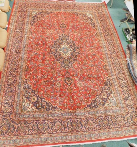 A large red ground Persian Mashed carpet, with central navy medallion, on a red floral ground with navy spandrels and multiple borders, 386cm x 299cm.