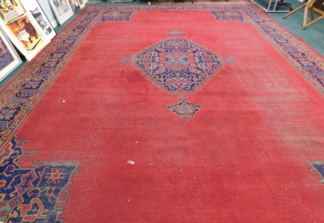 A 20thC Oriental rug, the inner field decorated with a floral arrangement in red and yellow on a blue ground, the outer border with further floral medallions, approx. 645cm long, 460 cm wide