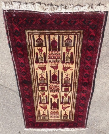 A Persian prayer rug, with a design of buildings, birds, etc. in deep red on a cream ground with multiple borders.