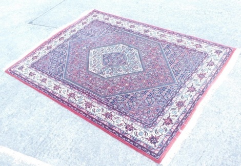 A pair of Indian Bidjir design wool rugs, each with an all over geometric pattern on a red ground with multiple borders, 203cm x 148cm.