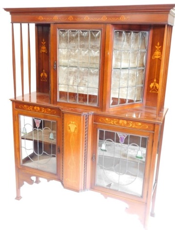 An Edwardian mahogany and marquetry display cabinet in the manner of Shapland & Petter, with a moulded cornice above a astragal glazed door flanked by two further panels, each with leaded divisions, the base with a moulded edge above two leaded glazed doo