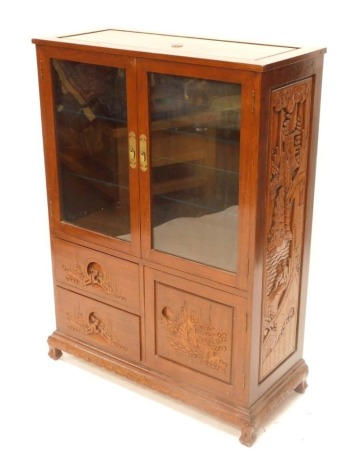 A Chinese hardwood side cabinet, with a panelled top over two glazed doors and two carved drawers and a door flanked by carved sides decorated with oriental ships, figures, etc., on carved feet, 116cm high, 83cm wide.