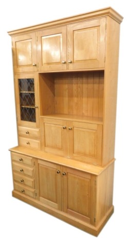 A craftsman made elm side cabinet, the top with an arrangement of panelled doors, a leaded glass door and drawers, the base with two further panelled doors, flanked by four side drawers on a plinth, 234cm high, 144cm wide.