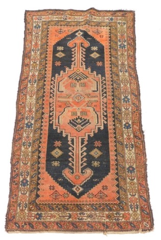 A Persian rug, with a central orange pole medallion, on a black ground with three geometric borders, 212cm x 112cm.