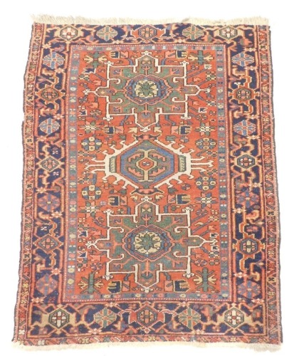 A Karaja rug, with three geometric medallions in blue, beige and green, on a red ground with one wide border, 136cm x 105cm.