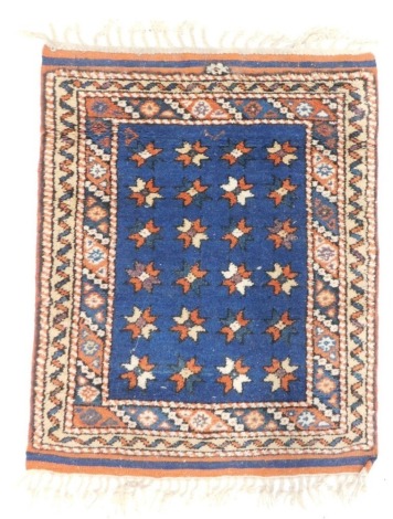 A small Persian rug or mat, with a star design, on a blue ground with multiple borders, 75cm x 59cm.