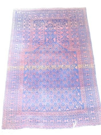 A Persian prayer rug, with a Mihrab, in navy on a red ground with one wide border, various narrow borders, 121cm x 81cm.