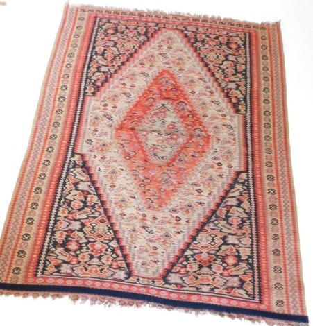 A Kilim rug, with a large central lozenge shaped medallion, in orange, red, gold, black and beige, within multiple borders, 121cm x 100cm.