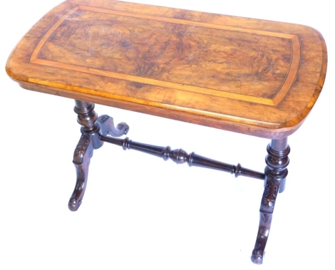 A Victorian walnut occasional table, the rectangular crossbanded top with shaped ends, on turned supports with stretcher and cabriole legs carved with leaves, 62cm high, 89cm wide.