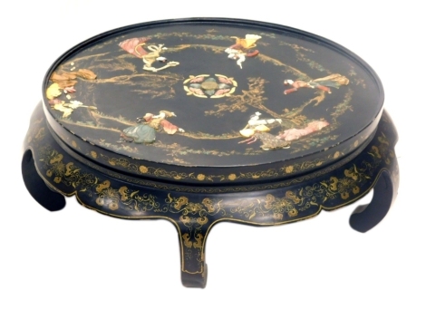 An oriental black lacquer coffee table, the top inlaid in coloured soapstone with figures, flowers, etc., embellished with gilt and painted borders, 89cm diameter.