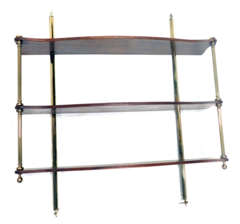 A mahogany and brass wall shelf, with three shaped tiers, on reeded pillar supports, 80cm high, 76cm wide.