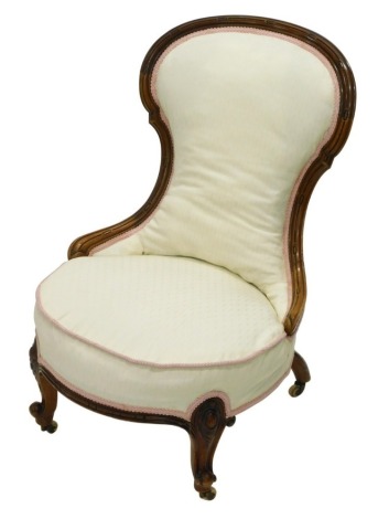 A Victorian walnut nursing chair, with a show frame, a padded back and seat, on cabriole legs with ceramic castors.