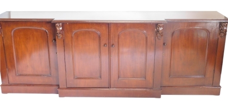 A mahogany sideboard in Victorian style, the top with a moulded edge above four drawers each with arched panels on a plinth, 84cm high, 239cm wide, 48cm deep.