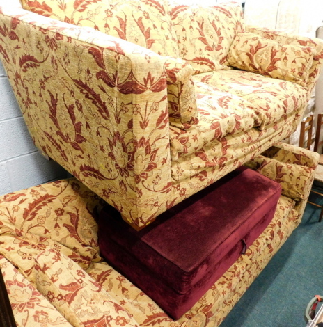 A matching two piece suite, comprising three seater and two seater settees, in yellow and floral pattern material, and a further footstool in pink, 105cm wide.