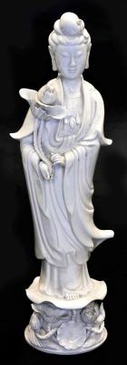 An early 20thC Chinese blanc de chine figure of Guan Yin, holding a lotus flower, on a floral embellished base, 47cm high.