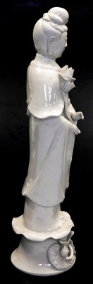 An early 20thC Chinese blanc de chine figure of Guan Yin, holding a lotus flower, on a floral embellished base, 47cm high. - 4