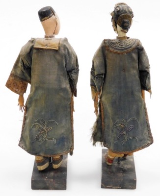Two Oriental figures, with pottery faces and embroidered clothing, on plinths, each 29cm high. (AF) - 3