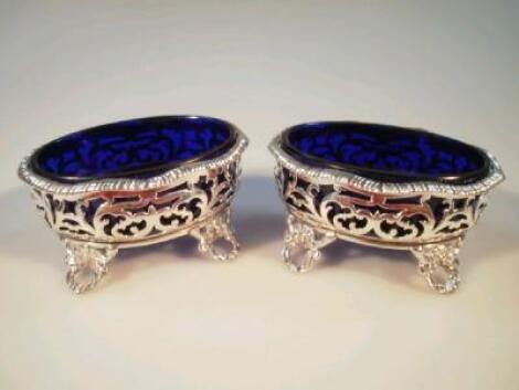 A pair of George III gadrooned oval salt cellars with leaf scrolls and