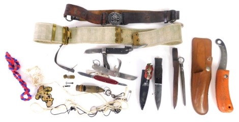 A leather Sam Browne belt, with Scout style medallion, folding knife, a sheath knife with cap badge to the sheath, the plain blade with jagged edge, etc. (a quantity)