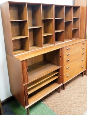 Two pieces of mid century teak lounge furniture, comprising a chest of five graduated long drawers, with an upper structure of open recesses, raised on turned legs, 170cm high, 90cm wide, 48cm deep, and a double tambour fronted cupboard enclosing shelves, - 2