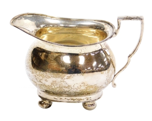 A George V silver cream jug, of plain form with angular handle, on four bun feet, John Deakin and Sons, Sheffield 1930, 3.76oz, 8.5cm high.