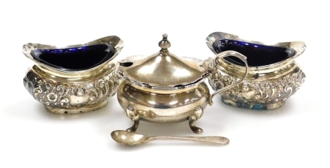 A pair of Edward VII open salts, embossed with flowers and scrolls, with blue glass liners, Birmingham 1907, and a Victorian mustard pot, with blue glass liner and spoon, weighable silver 4.34oz.