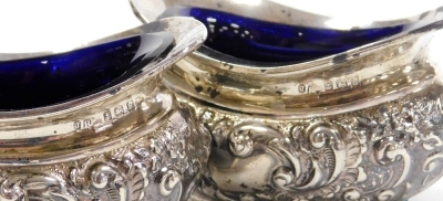 A pair of Edward VII open salts, embossed with flowers and scrolls, with blue glass liners, Birmingham 1907, and a Victorian mustard pot, with blue glass liner and spoon, weighable silver 4.34oz. - 3