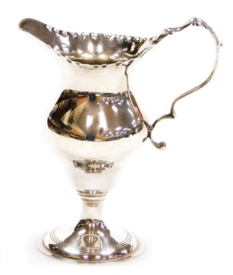 An Elizabeth II silver cream jug in the Georgian style, with a hammered rim and shaped handle with applied acanthus leaf thumb press, London 1969, 2.52oz, 10cm high.