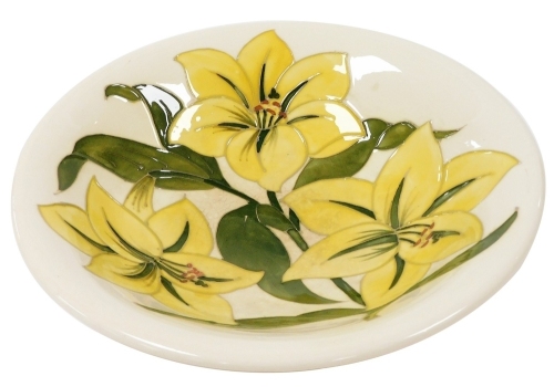 A Moorcroft Pottery dish decorated in the Bermuda Lily pattern, painted and impressed marks, 24.5cm diameter. (AF)