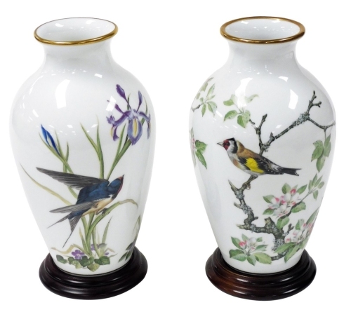 A pair of Franklin Mint porcelain bird vases, limited edition, circa 1980, with stands, comprising The Meadowland Bird vase, and The Woodland Bird vase, vases 29.5cm high.