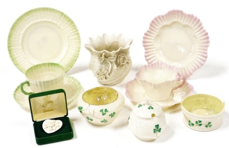 A group of Belleek porcelain, comprising a Neptune swirl vase encrusted with flowers, and a pink rimmed trio, second black mark, green bordered trio, shamrock decorated sugar bowl, mustard pot and cover, and butter tub, third black mark and a heart shaped