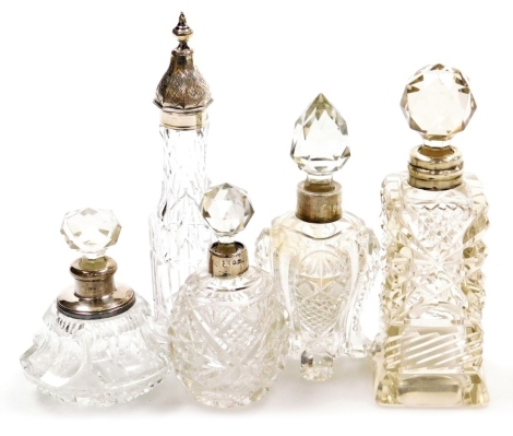 Five cut glass and silver mounted scent bottles, of differing shapes and designs, to include a cylindrical Victorian example, with a pagoda shaped silver top, circa 1880, 16cm high, etc.