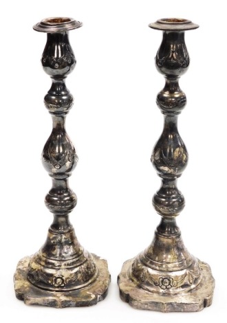 A pair of late 19thC Continental silver candlesticks, with embossed decoration, on a shaped square base, import mark, Martin Sugar, London 1897, 11.21oz, 28cm high.