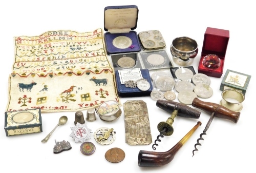 Various bygones and collectables, commemorative crowns, an Earl Mountbatten of Burma token, a 19thC alphabetic sampler (Jane ?), unframed, 27cm x 21cm, corkscrews, pipe, various badges, thimbles, plated napkin ring, etc. (1 tray)