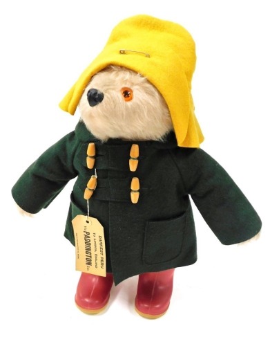 A Paddington Bear, wearing a yellow felt hat, green felt duffel coat, and red Wellington boots, 50cm high.