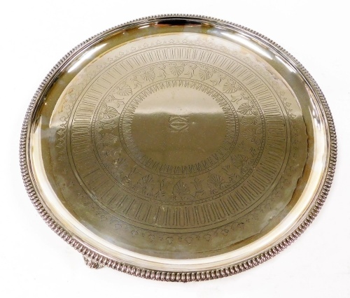 A Victorian Elkington & Company silver plated salver, with a gadrooned rim, engraved centrally with bands of acanthus and holly leaves, shamrocks, etc., centrally monogram engraved, raised on three scroll feet, impressed marks, 36cm wide.