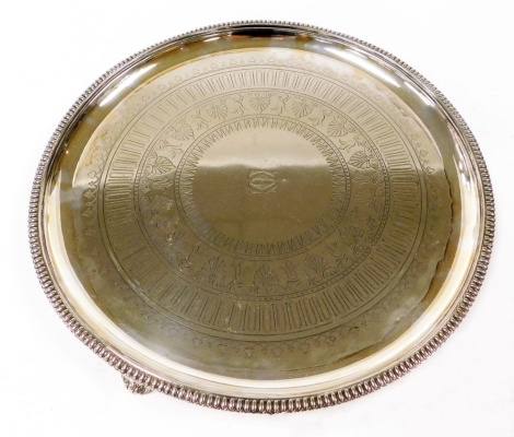 A Victorian Elkington & Company silver plated salver, with a gadrooned rim, engraved centrally with bands of acanthus and holly leaves, shamrocks, etc., centrally monogram engraved, raised on three scroll feet, impressed marks, 36cm wide.