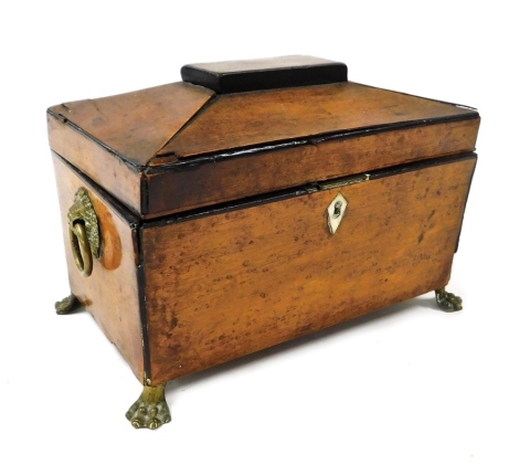 A Georgian burr yew tea caddy, of sarcophagus form, with brass lion's head and ring handles, opening to reveal a vacant interior, raised on brass lion's paw feet, 22cm wide.